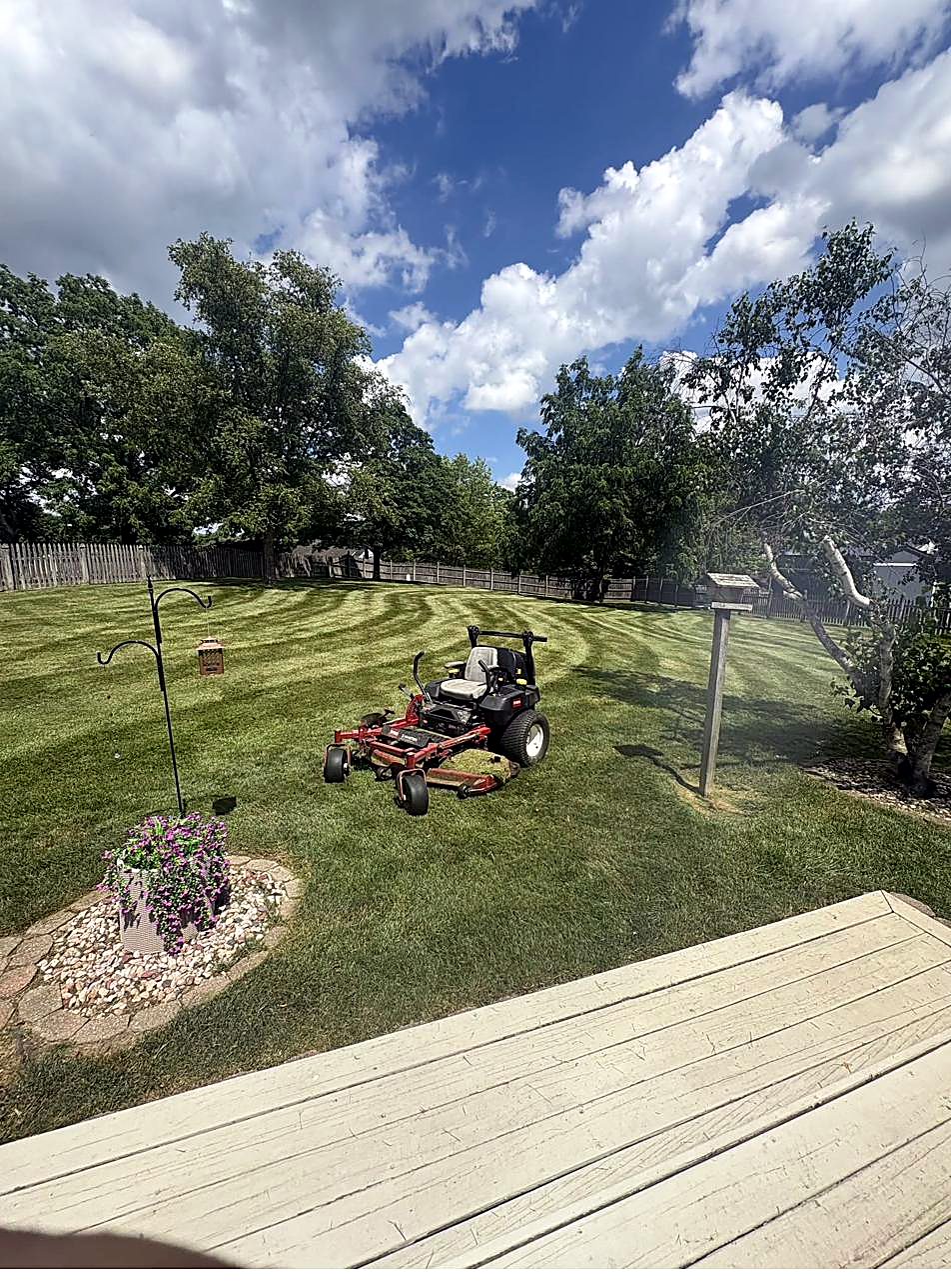 Zero-turn mower on a freshly striped lawn in front of a home